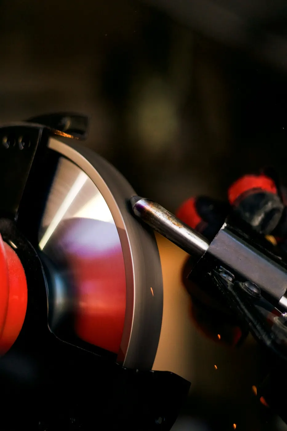 A grinding wheel spinning on a bench grinder in a metal workshop.